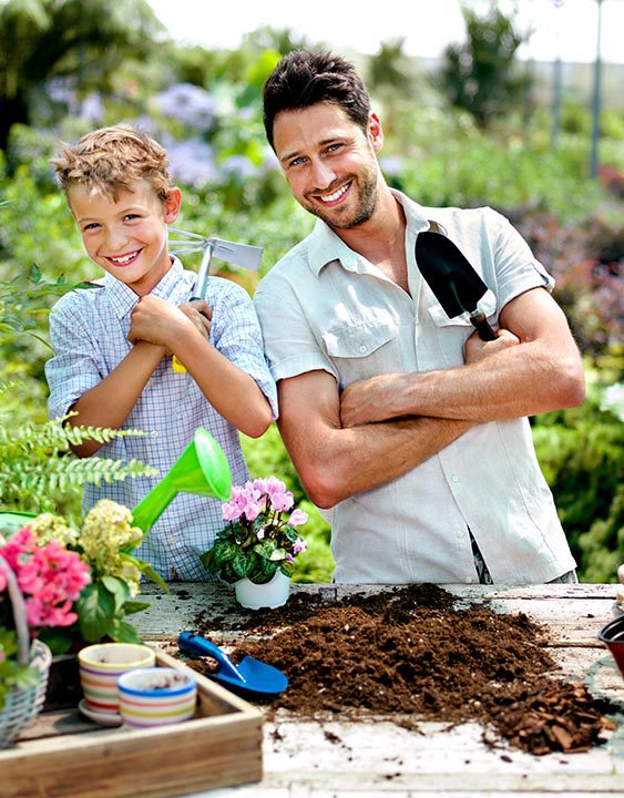 father and son playing with work tools in a greenhouse